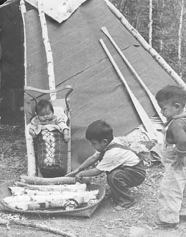 Old photo of children at camp with firewood